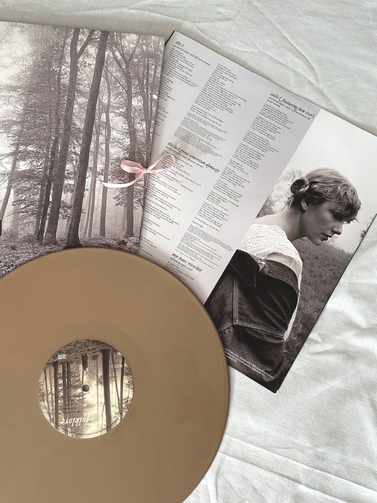 an open magazine and a gold colored disc on a white sheet with trees in the background