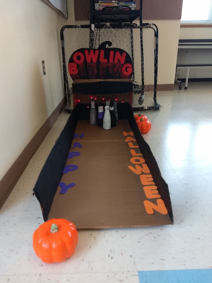 an indoor bowling game with pumpkins on the floor in front of it and a sign that says bowling