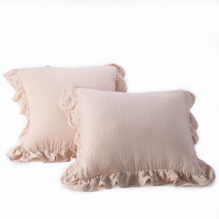 two pink pillows with ruffled edges on a white background, one in the foreground and the other in the back ground