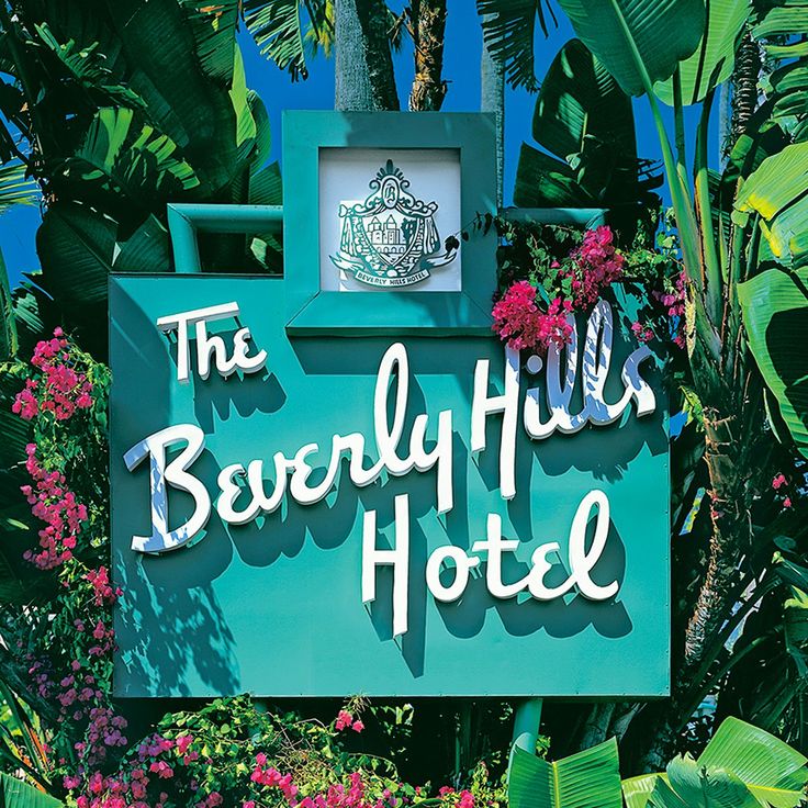 the beverly hills hotel sign surrounded by tropical plants