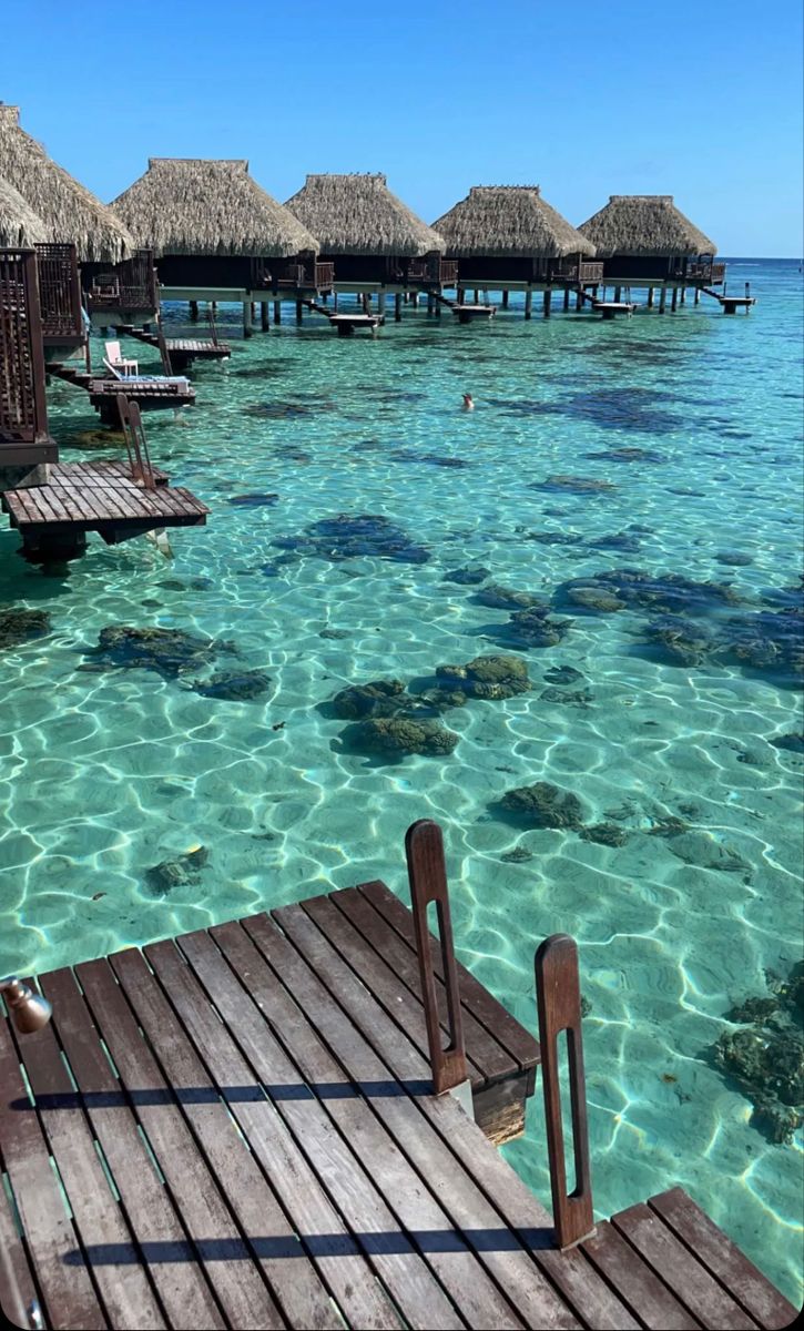 the water is crystal blue and clear with some huts on it's docks