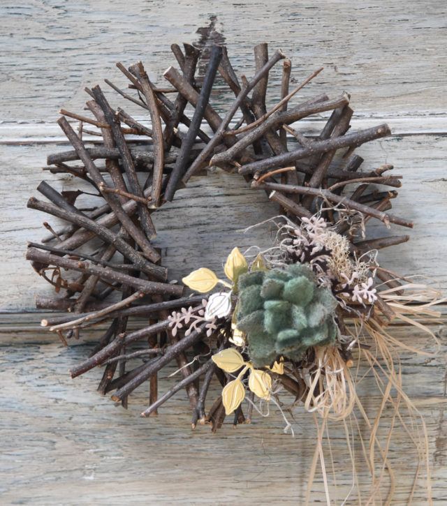 a wreath made out of branches and twigs with a succulent plant on top