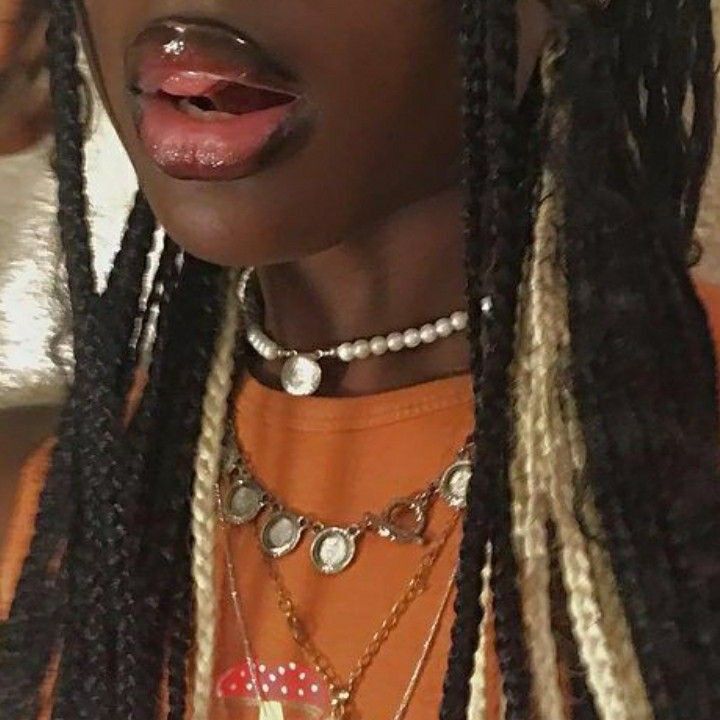 a close up of a person with dreadlocks wearing an orange t - shirt