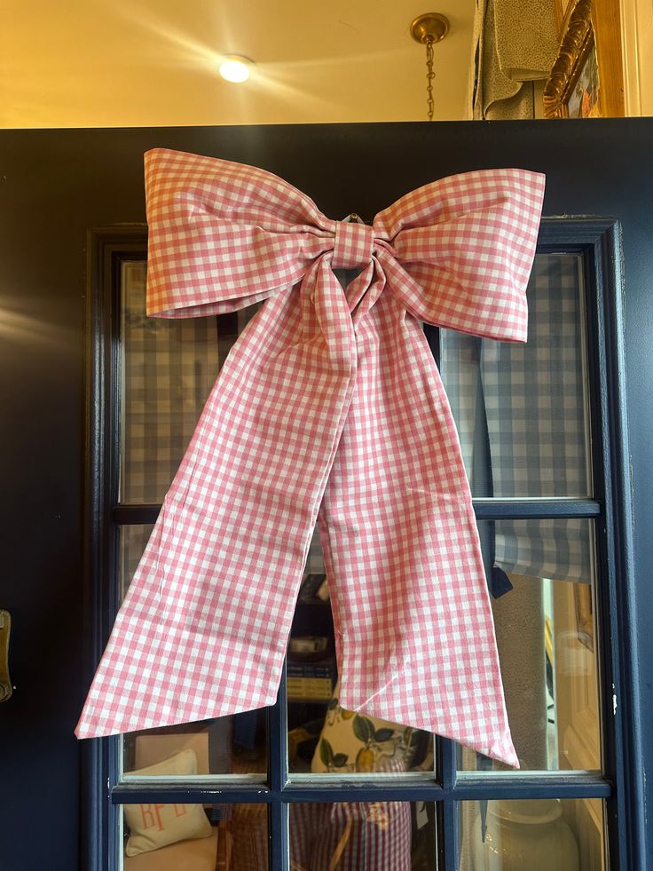 a red and white gingham bow hanging on the front door