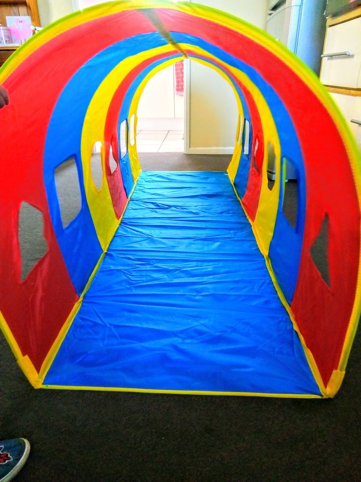 a child's play tunnel in the middle of a room with blue and red carpet