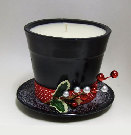 a candle is sitting on top of a black hat with holly berries and white pearls