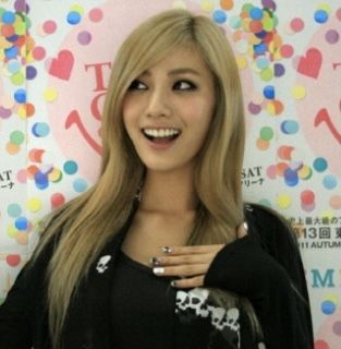 a woman with long blonde hair standing in front of a colorful wall and smiling at the camera