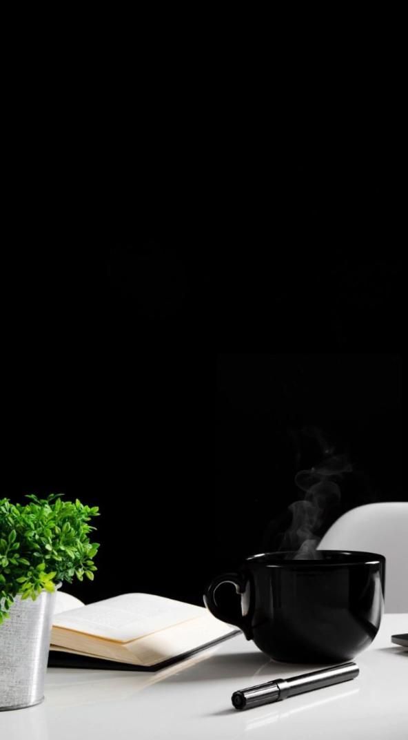 a white table topped with a cup of coffee next to a potted plant and an open book