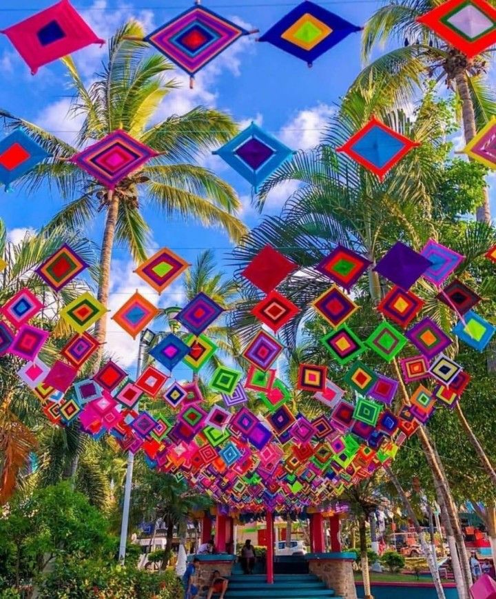 many colorful squares are hanging from the ceiling in front of palm trees and blue sky