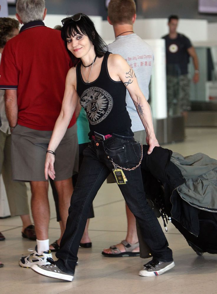 a woman with black hair and piercings is carrying her luggage in an airport terminal