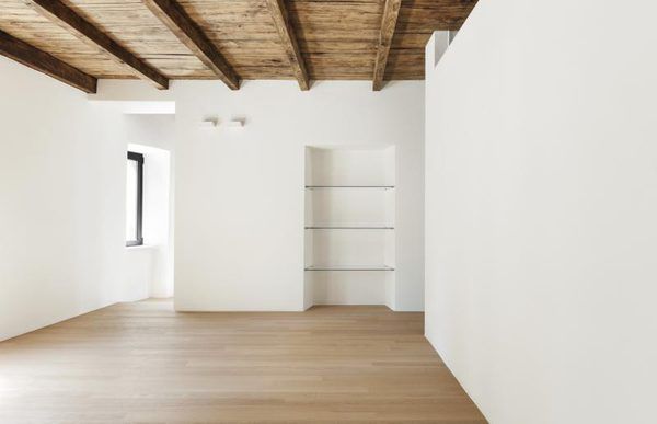 an empty white room with wooden floors and exposed beams on the ceiling is seen in this image