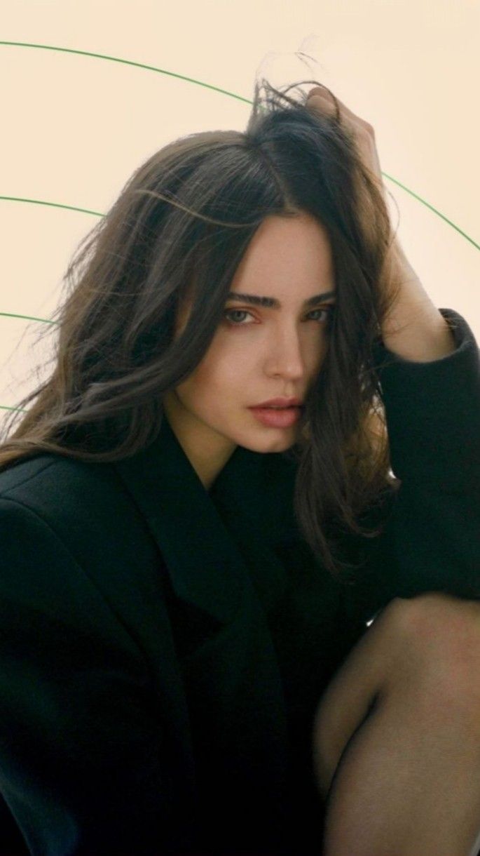 a woman with long hair sitting on the ground