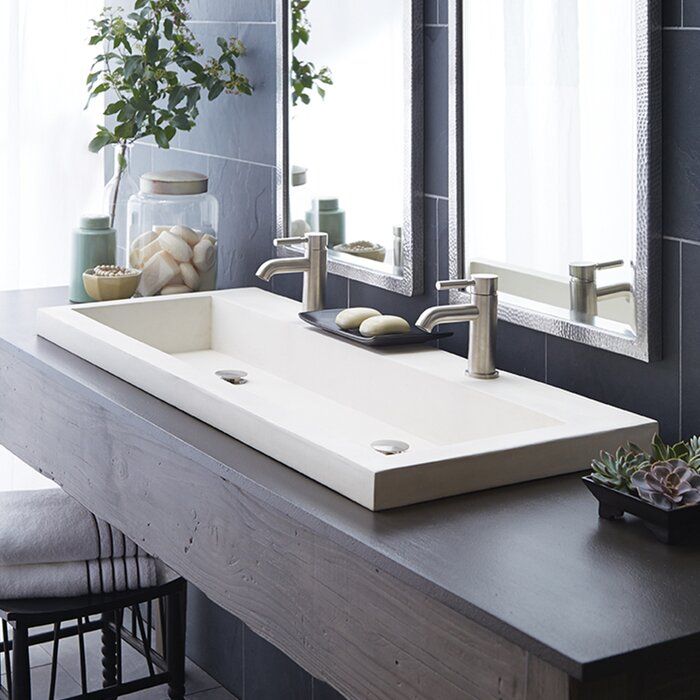 a bathroom sink sitting under a mirror next to a counter with a potted plant on it