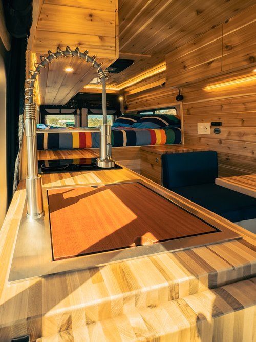 the inside of a bus with wooden floors and bunk beds on each side, in front of a wood paneled wall