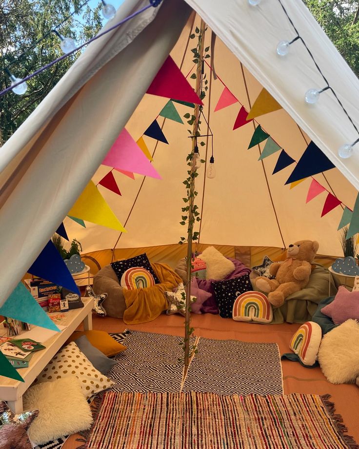 a teepee tent with lots of pillows and stuffed animals in the inside, including a teddy bear