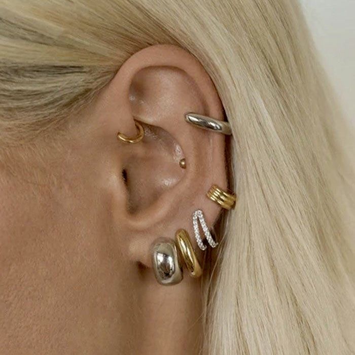 a woman with blonde hair wearing three different ear piercings