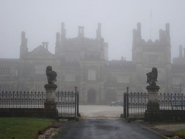 an old building with statues in front of it on a foggy day at the entrance