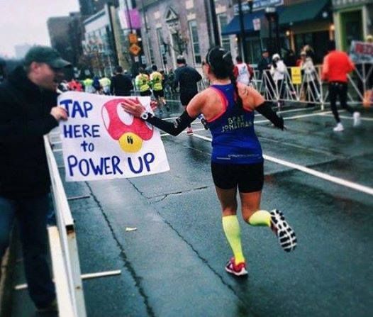 a woman running down the street with a sign that says tap here to power up