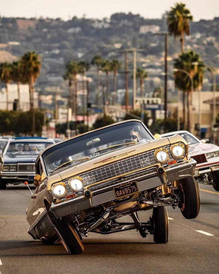 an old car that is upside down on the road with other cars in the background