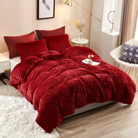 a bed with red comforter and pillows in a room