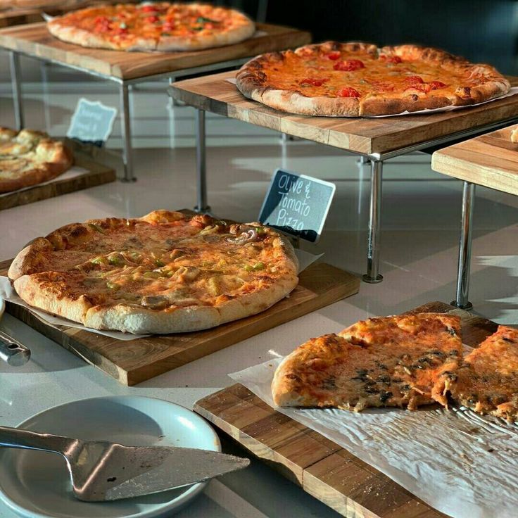 several different types of pizzas on wooden trays and serving platters ...