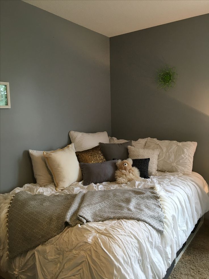 a bed with pillows and blankets on top of it in a room that has gray walls