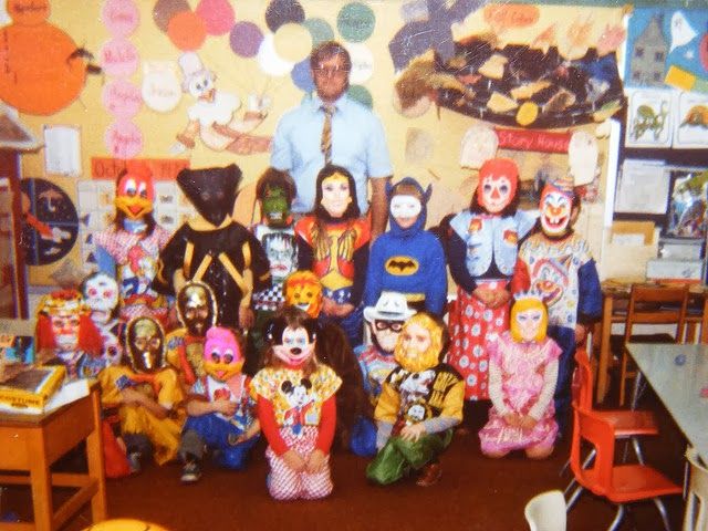 a group of people dressed up in costumes posing for a photo with clowns on the wall behind them