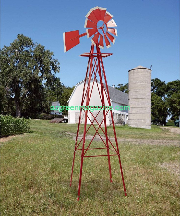 a red and white windmill sitting on top of a lush green field