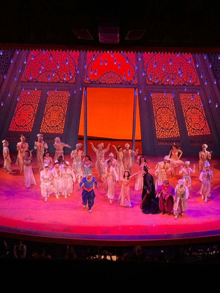 a group of people standing on top of a stage in front of a red curtain