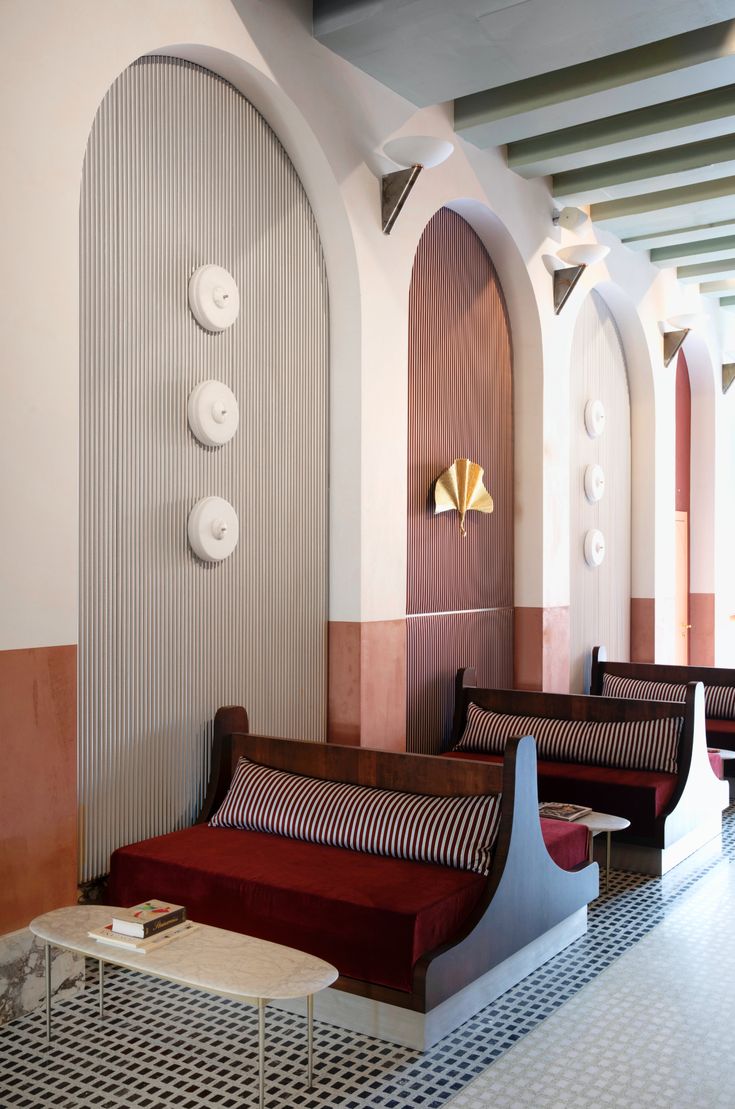 the interior of a resturant with red and white couches, round mirrors and circular lights