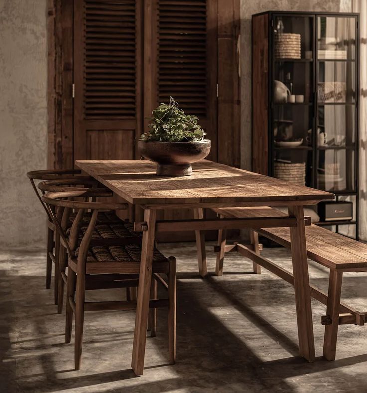 a wooden table with four chairs and a potted plant sitting on top of it