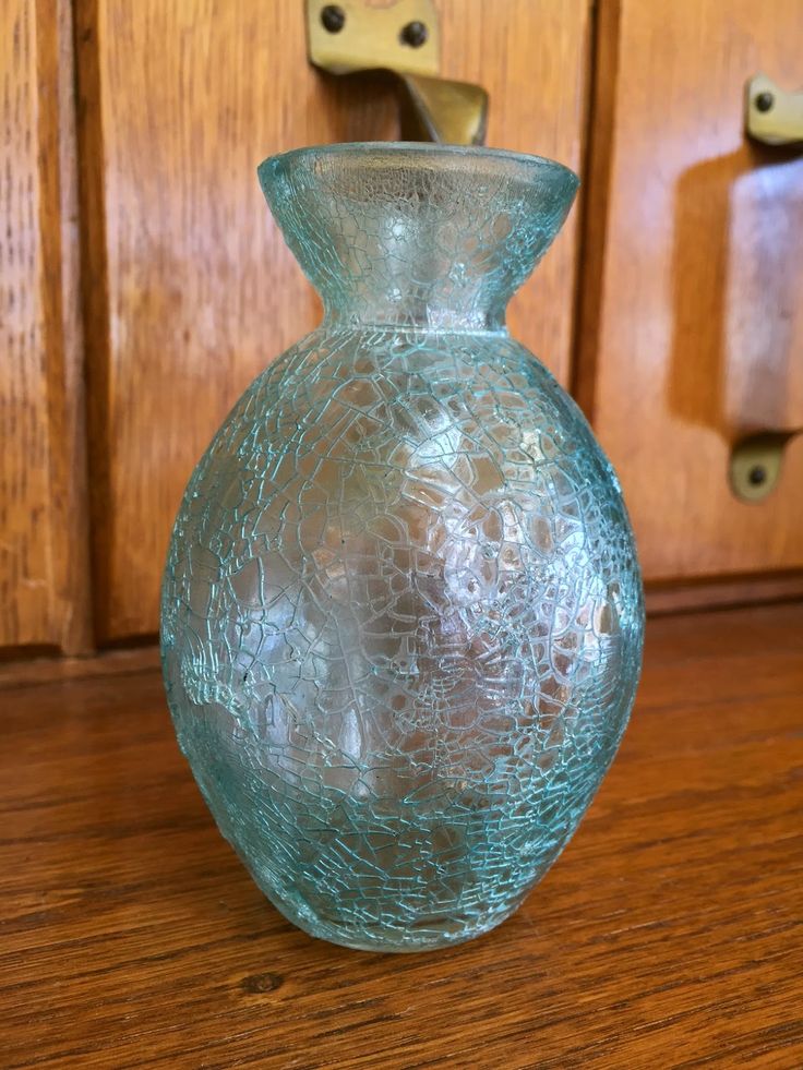 a blue glass vase sitting on top of a wooden table next to a light switch