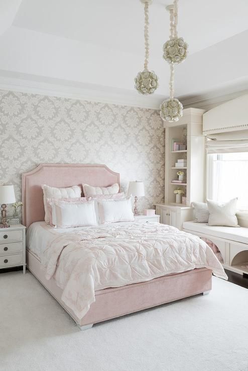 a bedroom with a pink bed and white carpeted flooring in front of a window