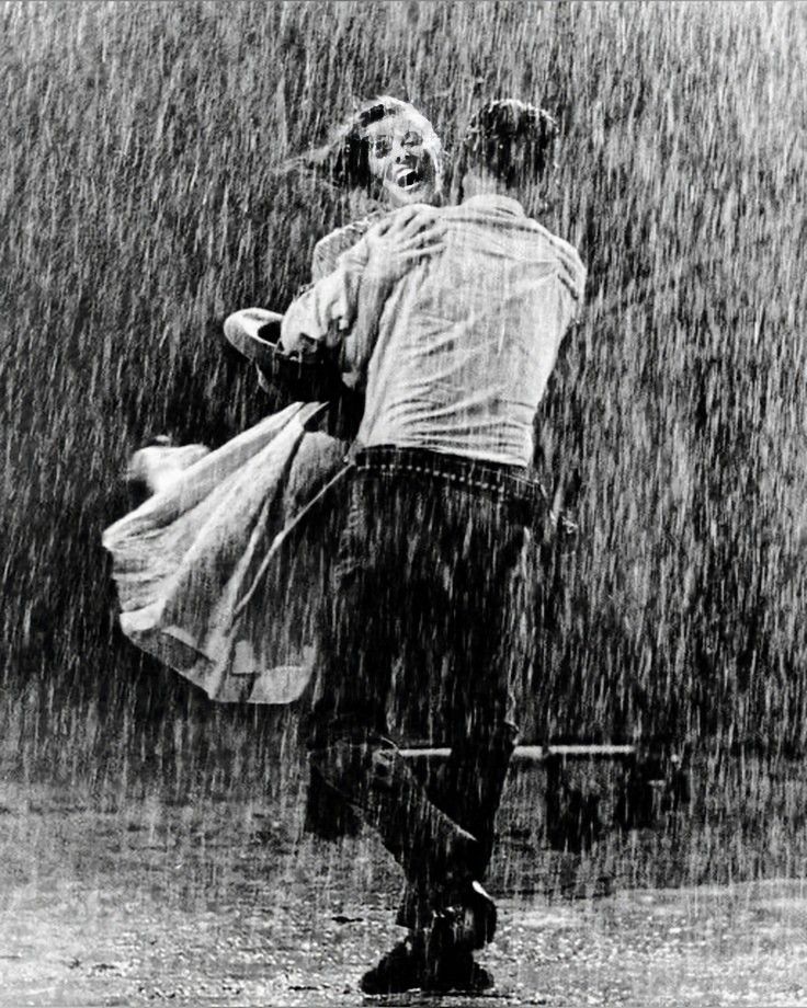 black and white photograph of two people in the rain, one holding the other's back