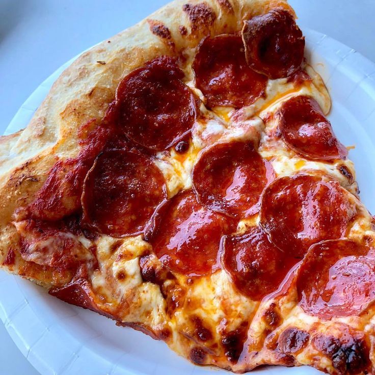 a slice of pepperoni pizza on a white plate