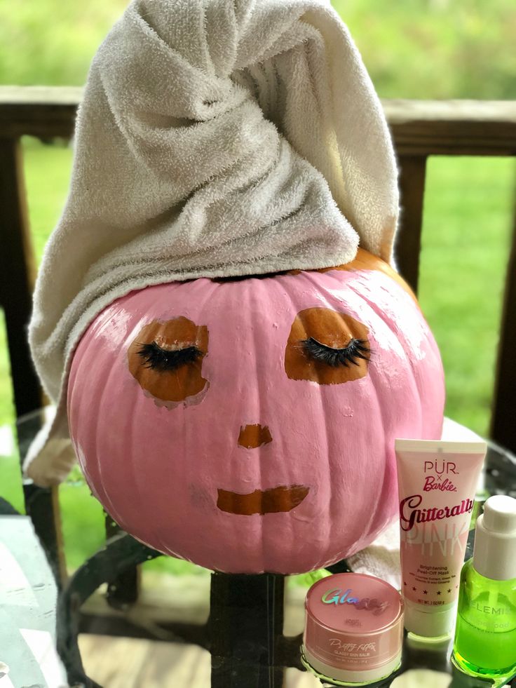 a pink pumpkin with a towel on it's head and some other items around it