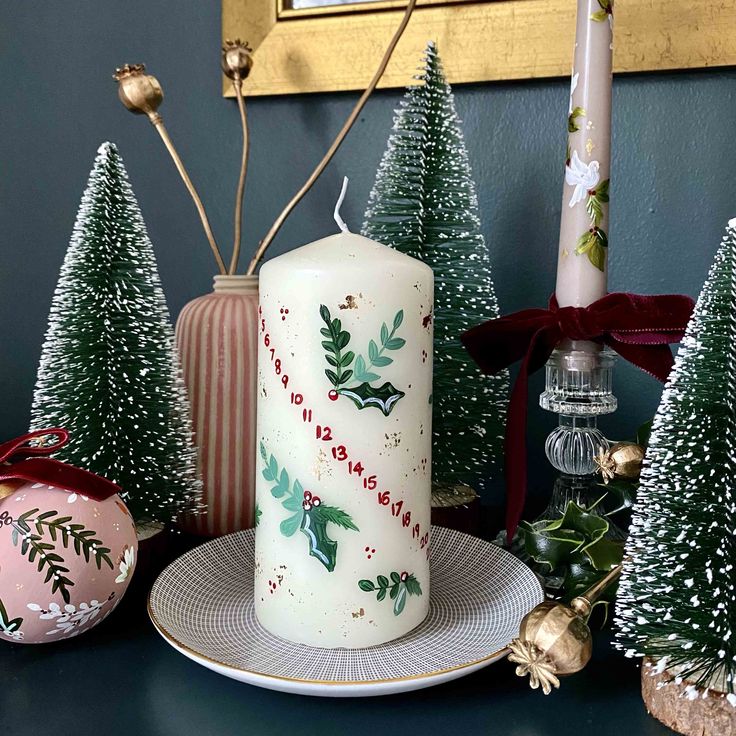 a lit candle sitting on top of a plate next to christmas trees