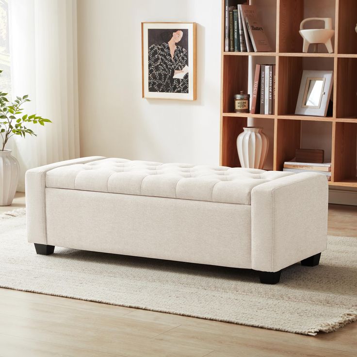 a white bench sitting on top of a wooden floor next to a book shelf filled with books