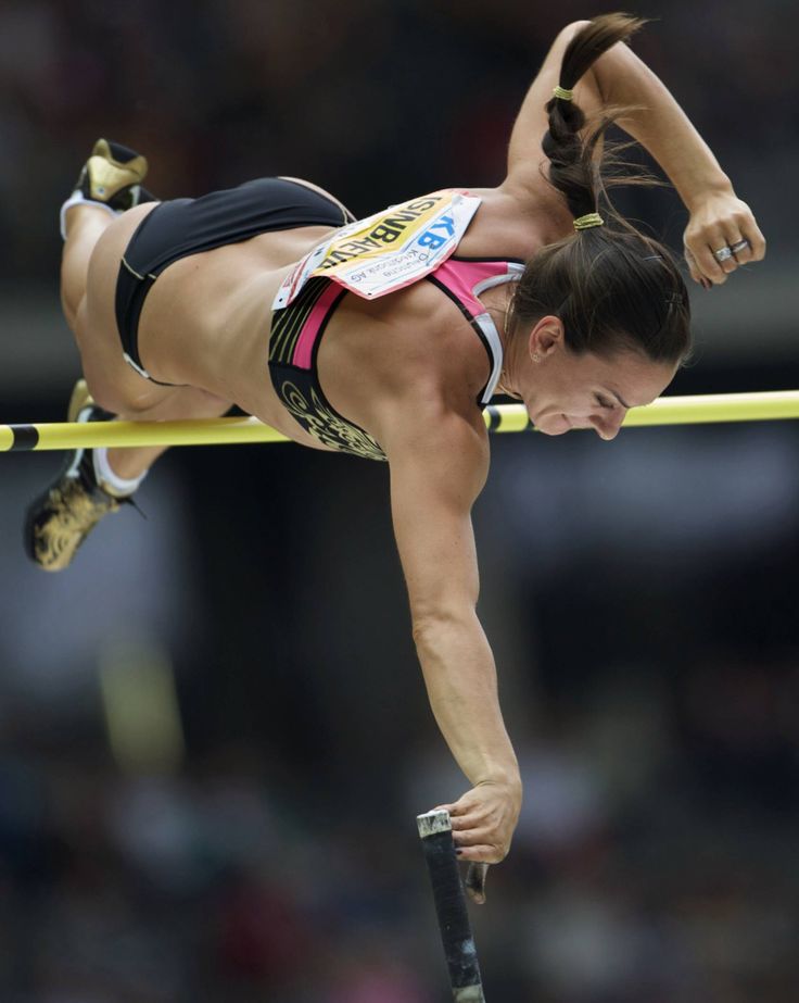 a woman is doing an aerial trick on a pole in the middle of a competition