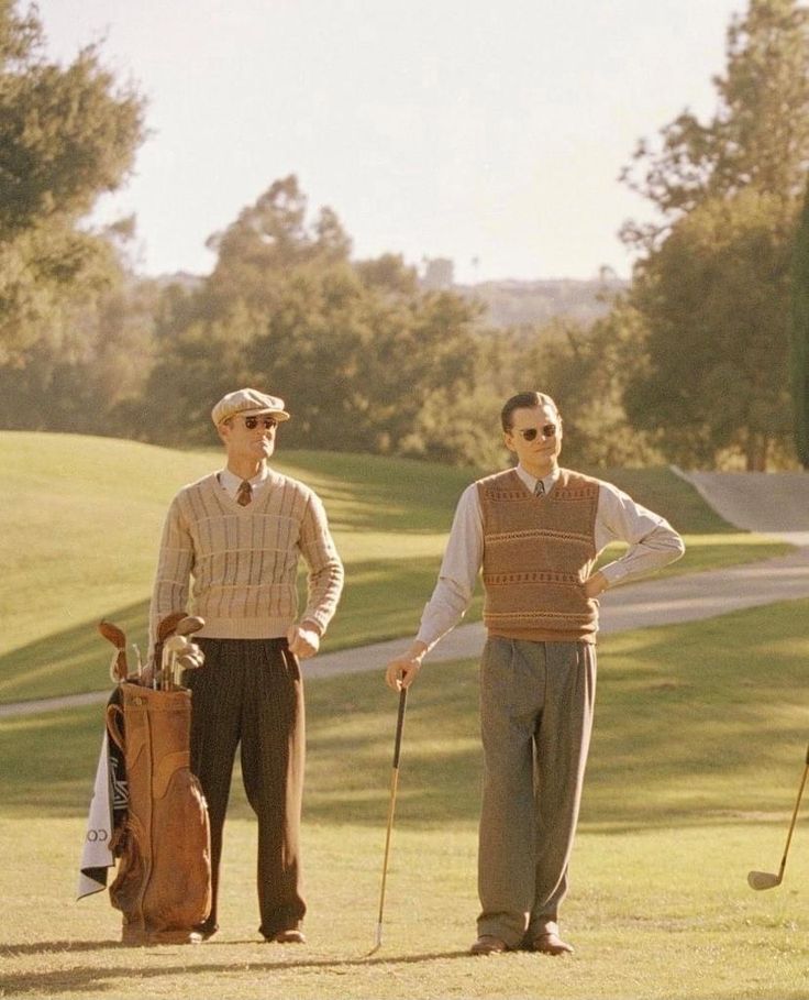 two men standing next to each other holding golf clubs