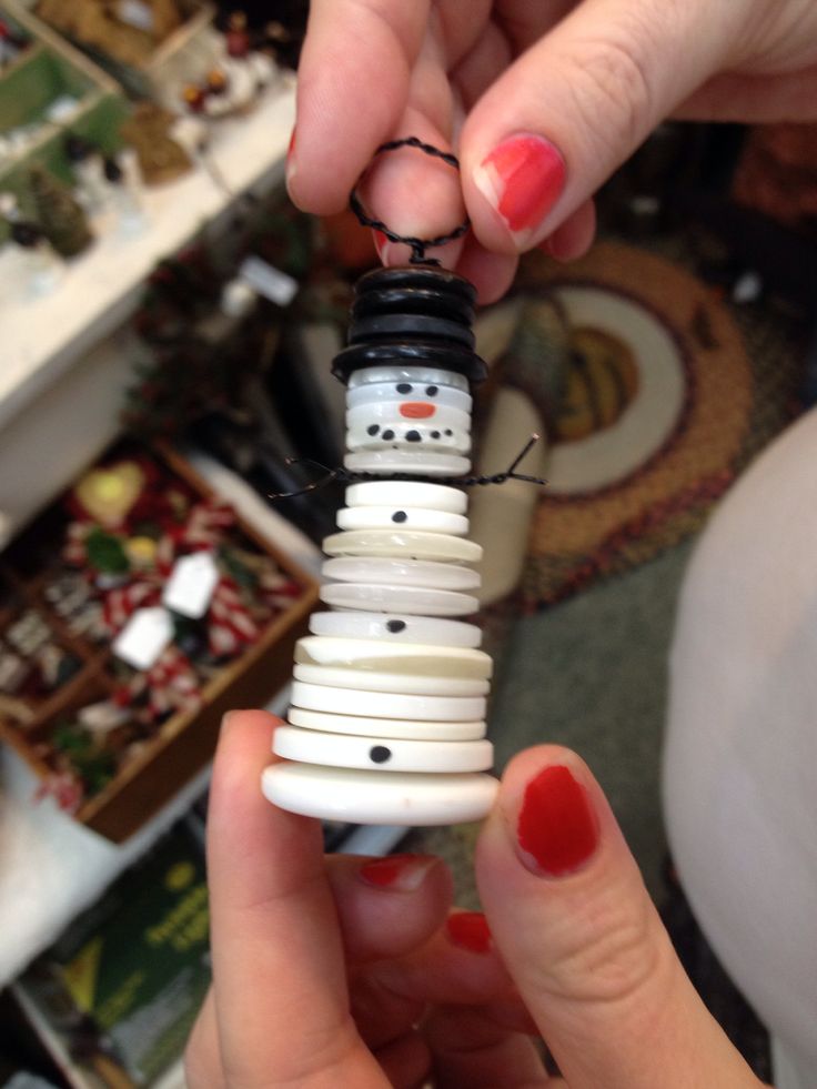 a person holding a snowman ornament made out of buttons