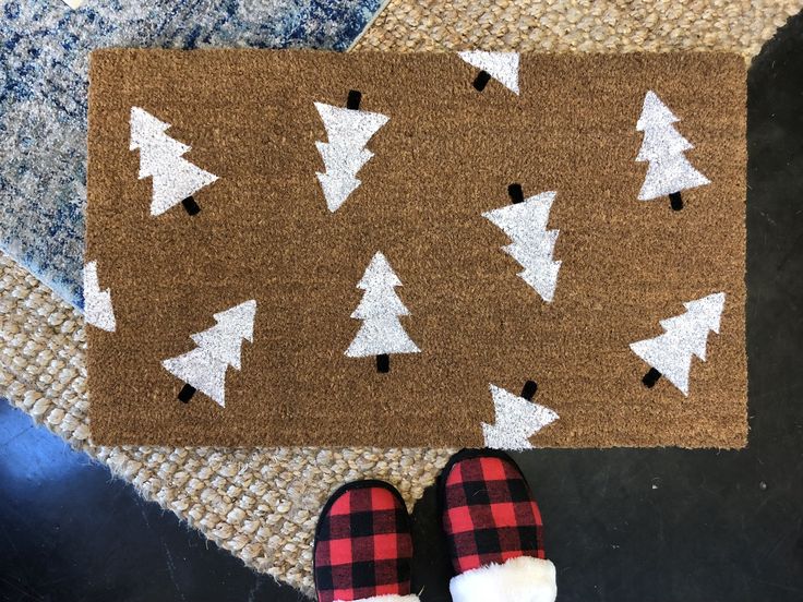 someone is standing in front of a door mat with christmas trees on it