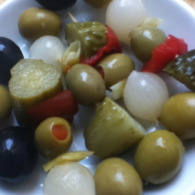 an assortment of olives and peppers on a white plate