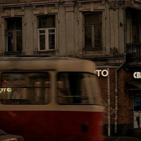 a red and white bus driving past a tall building