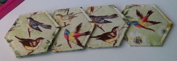 four small coasters with birds on them sitting next to a pen and pencil holder