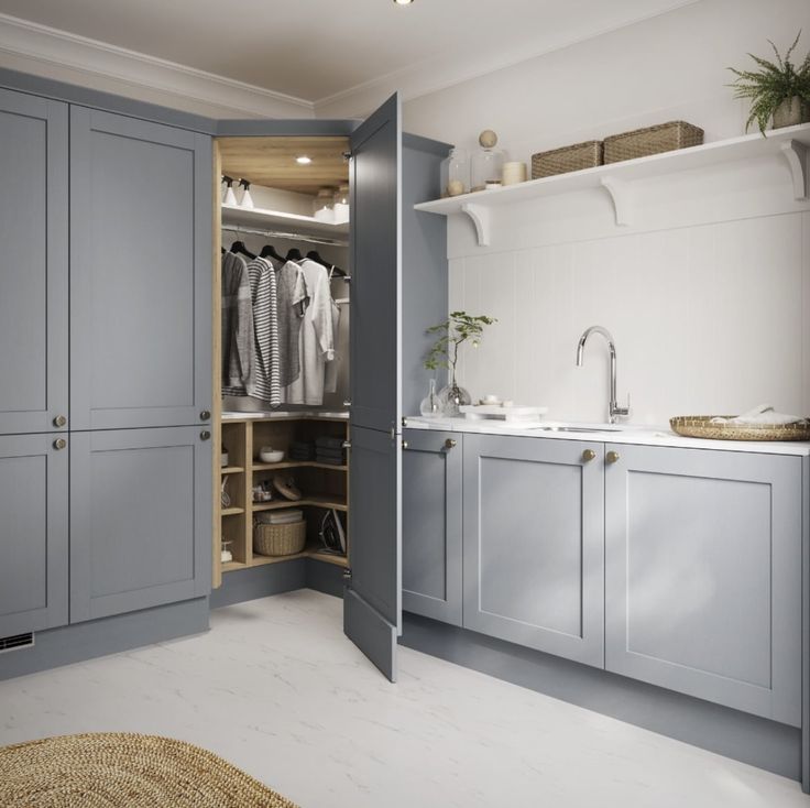 an open closet in the middle of a kitchen with grey cabinets and white counter tops