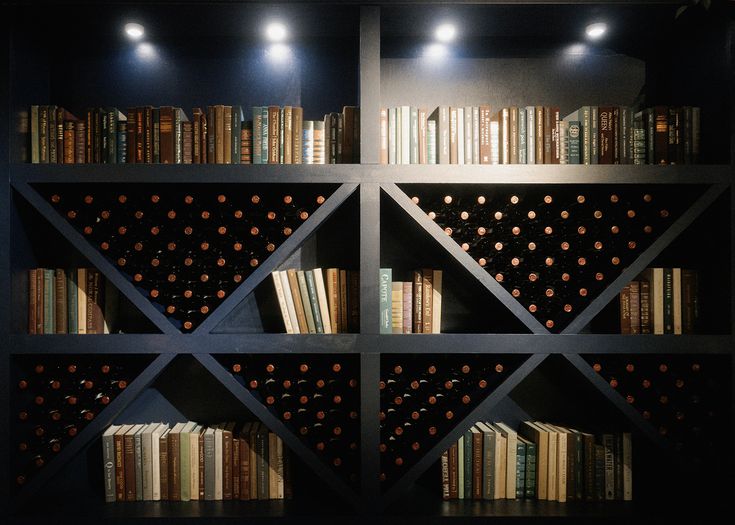 a bookshelf filled with lots of books next to lights on the walls and floor