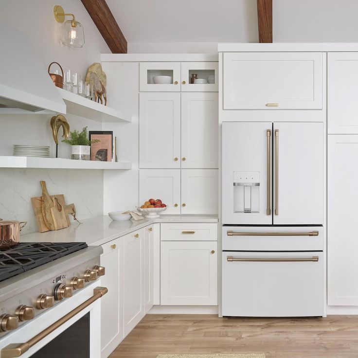 a kitchen with white cabinets and gold trim on the oven, counter tops and drawers