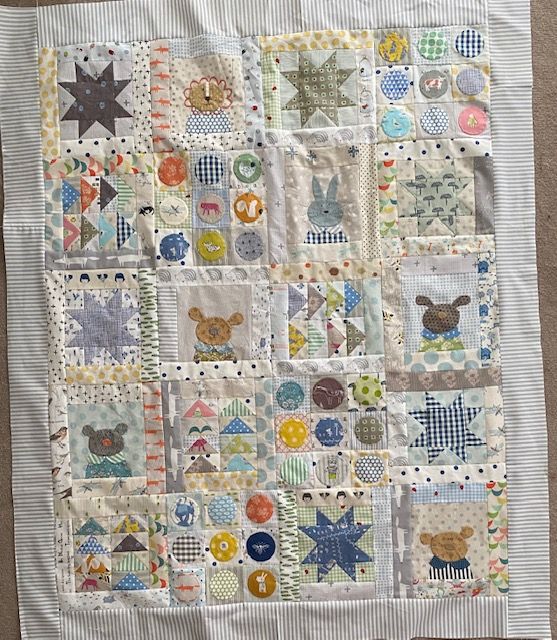 a quilted wall hanging on the side of a bed with teddy bears and stars