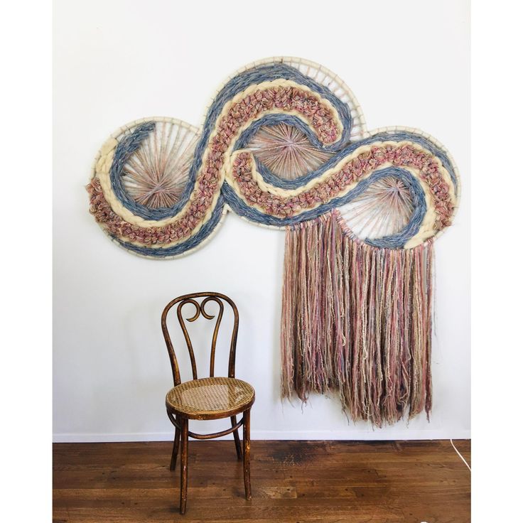 a chair sitting in front of a wall hanging with two circular objects on it's side